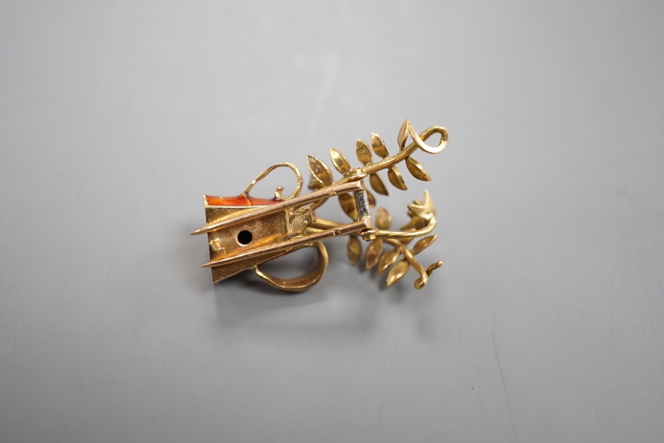 A French yellow metal (18ct poincon mark), two colour enamel, ruby and diamond set novelty brooch, modelled as a tyg with foliate stems, signed Marcel Pac, Paris, 29mm, gross weight 5.8 grams.